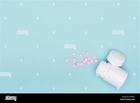 medication bottle and white pills spilled on blue pastel colored background medication and