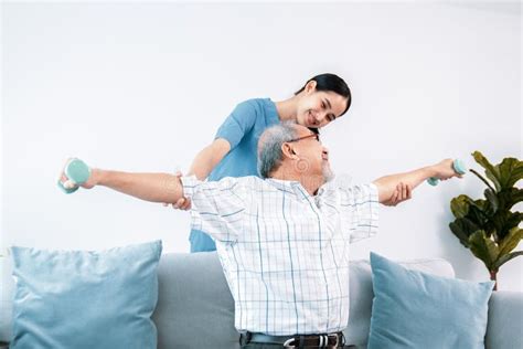 Contented Senior Patient Doing Physical Therapy With The Help Of His