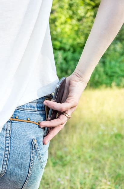 Premium Photo A Woman Puts A Smartphone In The Back Pocket Of Jeans