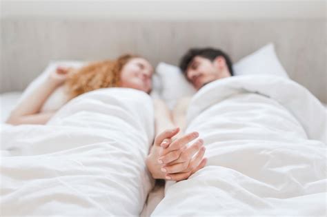 Couple Holding Hands While Lying On Bed Photo Free Download