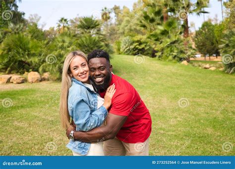 Happy Interracial Couple Hugging In Park Looking At Camera For Photo They Are Happy And Excited
