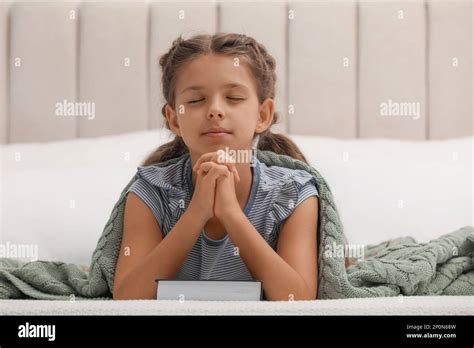 Cute Little Girl Praying Over Bible In Bedroom Stock Photo Alamy
