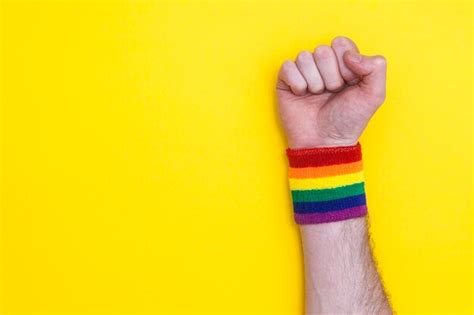 Premium Photo Fist Hand With Gay Pride Rainbow Flag Wristband On A Yellow Background