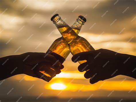 Premium Photo Couple Hands Holding Beer Bottles And Clanging On The Sunset Beach