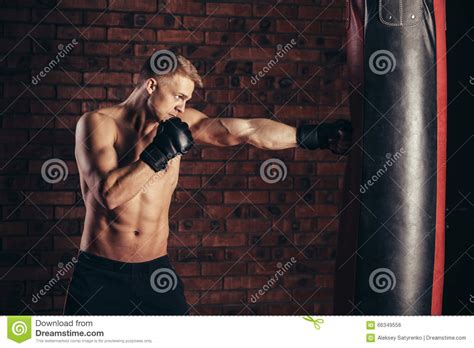 ein junger boxer in den schwarzen handschuhen mit einem nackten torso arbeiten streiks auf