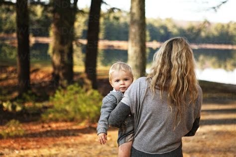 Rear View Of Woman Carrying Baby While Walking On Field Stock Photo