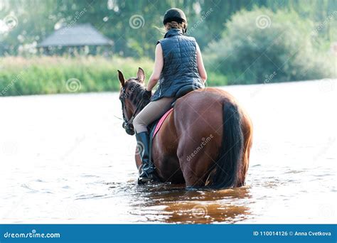 Young Teenage Girl Riding Horseback In River At Early Morning Stock