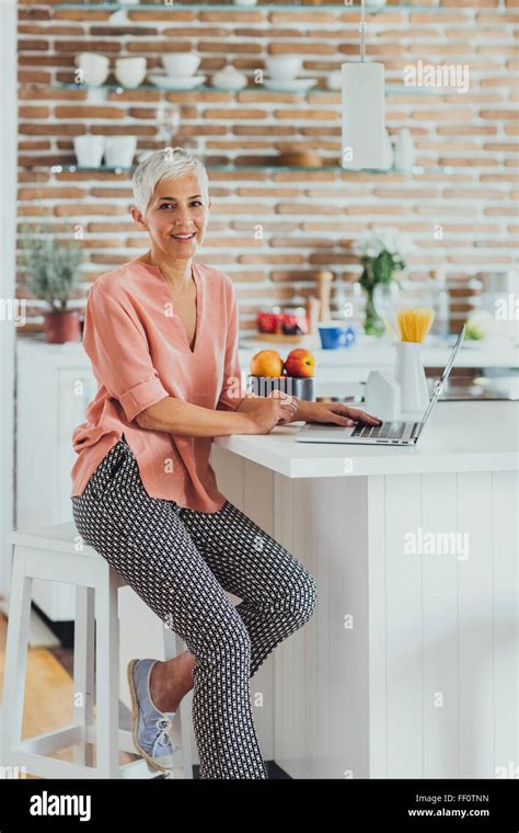 Older Caucasian Woman Using Laptop In Kitchen Stock Photo Alamy