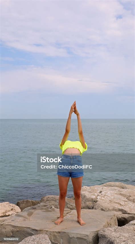 Girl In A Shirt Giving A Gymnastic Exercise On The Rocks Arching Her Back Backwards And Her Head