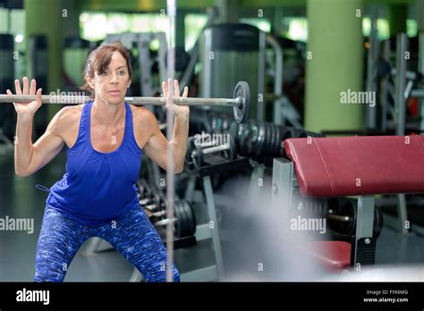 A Mature Retired Woman Keeping In Shape By Lifting Weights At The Gym