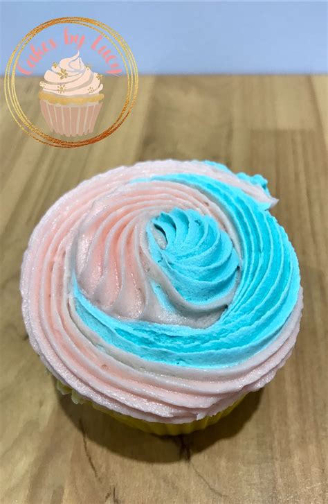 a cupcake with blue and pink frosting sitting on top of a wooden table