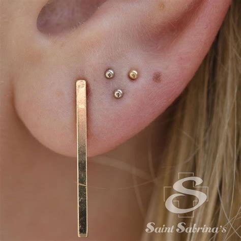 A Close Up Of A Person S Ear With Three Small Studs On It