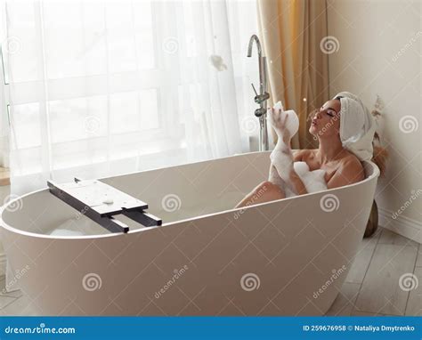 Caucasian Happy Attractive Woman Lying In Bathtub Naked With Towel On Head Having Fun Relaxing