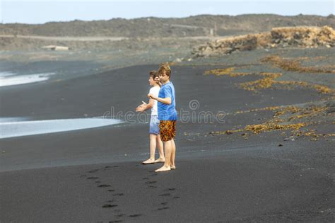 Deux Gar Ons De L Adolescence Ont L Amusement Une Plage Volcanique Noire Photo Stock Image