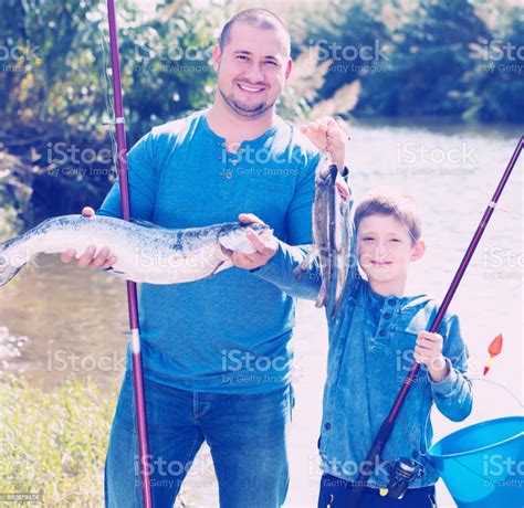 Smiling Father And Son Fishing With Rods Stock Photo Download Image
