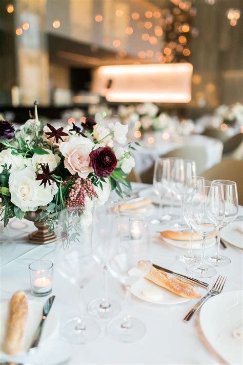 Ivory Blush And Burgundy Centerpiece In A Gold Vase With Lush Greenery