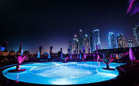 An Illuminated Swimming Pool In The Middle Of A City At Night With