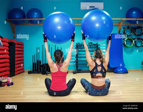 Two Young Women Exercising In Gym Using Inflatable Exercise Ba Stock