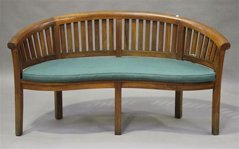A Modern Teak Banana Garden Bench Of Curved Form Fitted With A Cushion Height 84cm Width 159cm D