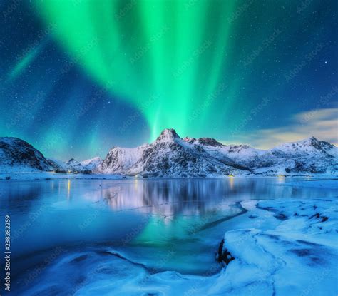 Aurora Borealis Over Snowy Mountains Frozen Sea Coast And Reflection