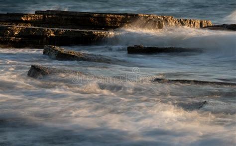Stormy Windy Sea Waves Splashing On A Rocky Seashore At Sunset Stock