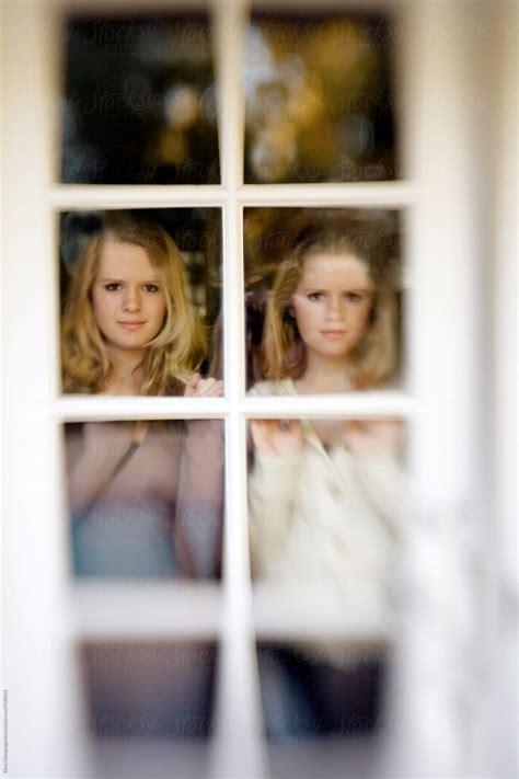 Twin Girls Looking Out Glass Door By Stocksy Contributor Dina Marie Giangregorio Stocksy