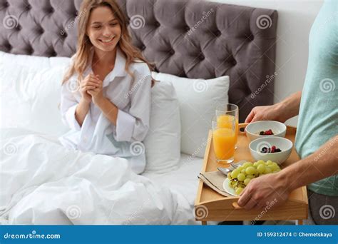 Young Man Bringing Romantic Breakfast To His Girlfriend In Bed Stock