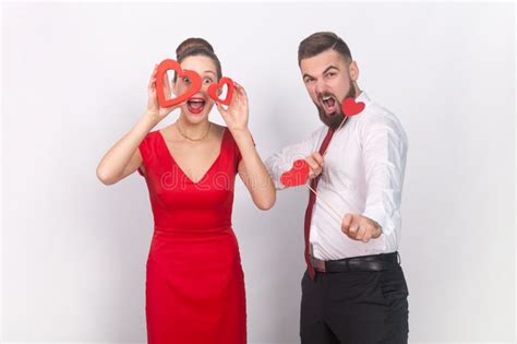 Crazy Man And Amazed Woman In Red Dress Standing Together Holding