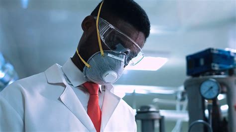 Side view of black scientist in white lab coat, goggles ...