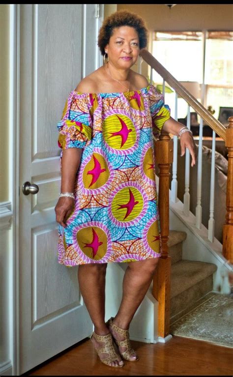 A Woman In A Colorful Dress Standing Next To A Stair Case And Looking