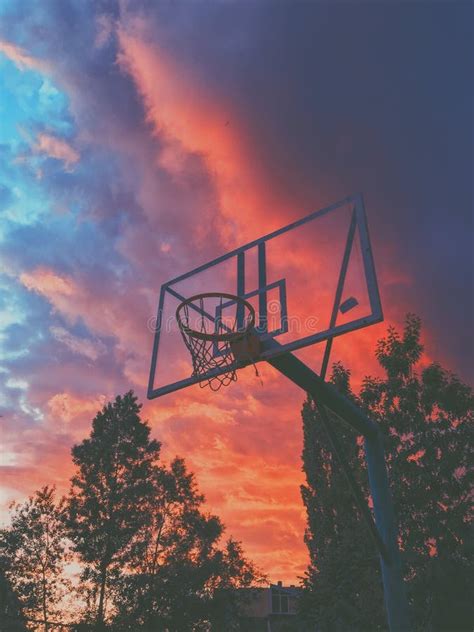 Vertical Shot Of A Basketball Hoop In A Field With A Beautiful Red Sky