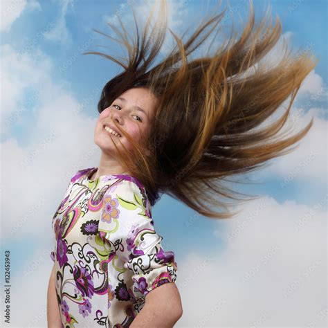 Teenage Girl With Flowing Hair Flying In The Wind On Cloudy Blue Sky