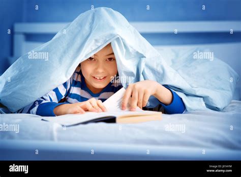 Boy Lying In Bed With A Book Stock Photo Alamy