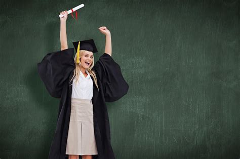 Premium Photo Blonde Student In Graduate Robe Holding Up Her Diploma