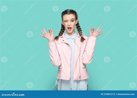 playful teenager girl standing showing okay sign winking to camera expressing positive