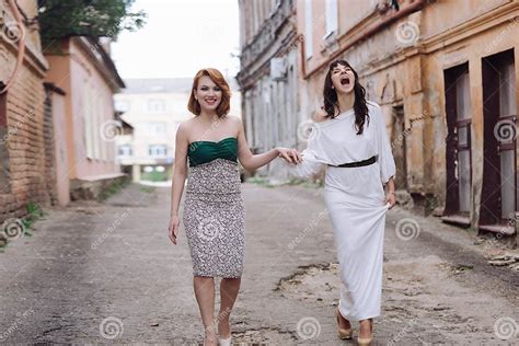 Two Beautiful Women Walking On The Street Holding Hands Talking Stock