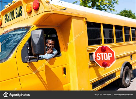 Smiling Mature African American Bus Driver Looking Out Window Gesturing