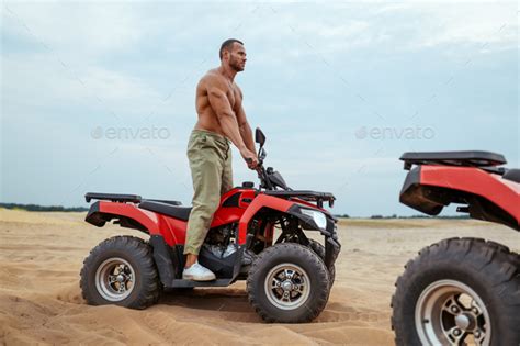 Brutal Man With Naked Body Rides On Atv In Desert Stock Photo By NomadSoul