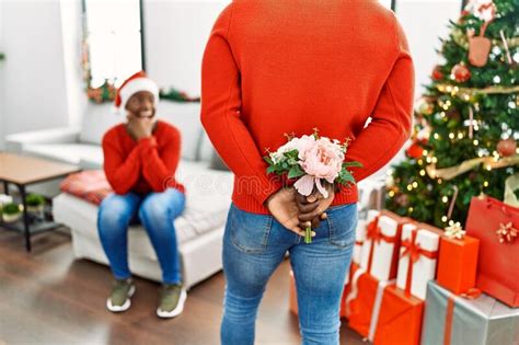 African American Man Surprising His Girlfriend With Bouquet Of Flowers At Home Stock Image