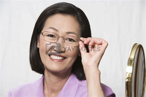 Portrait Of A Mature Chinese Woman Trying On Glasses Over Grey