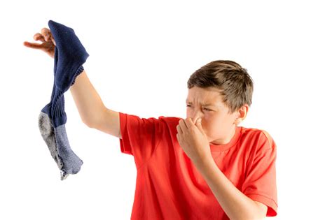 Young Teenage Boy Isolated On A White Background Holding A Smelly Sock