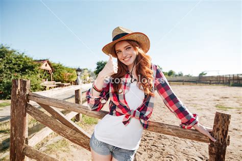 Smiling Cheerful Redhead Cowgirl In Hat Showing Thumbs Up Gesture While