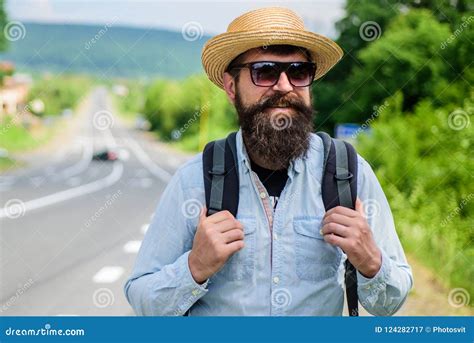 tips of experienced backpacker man bearded hipster backpacker at edge of highway pick me up