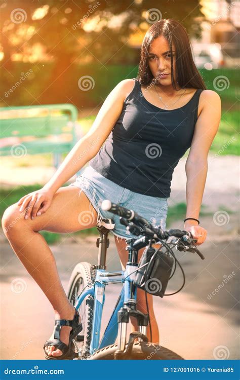 Young Pretty Brunette Girl In Denim Shorts With A Bicycle On The Street