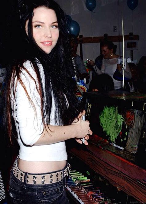 A Woman With Long Hair Standing In Front Of A Piano