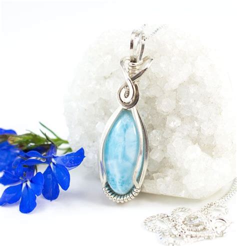 A Necklace With A Blue Tear Shaped Stone On It Next To Some White Rocks