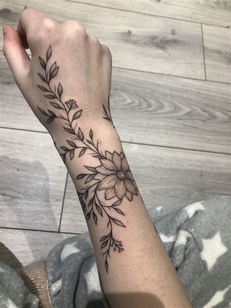 A Womans Arm With A Flower Tattoo On The Left Side Of Her Wrist