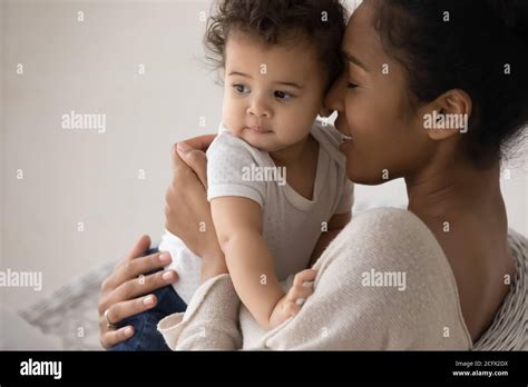 Caring Young Mixed Race Mother Cuddling Little Biracial Baby Stock