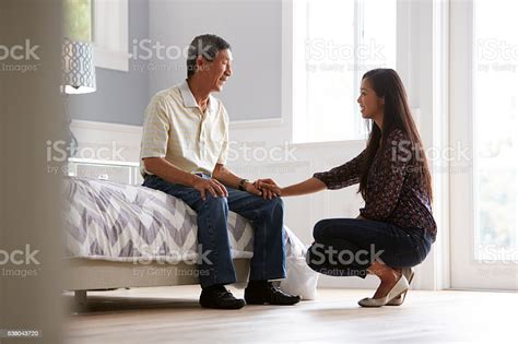 Adult Daughter Talking To Depressed Father At Home Stock Photo
