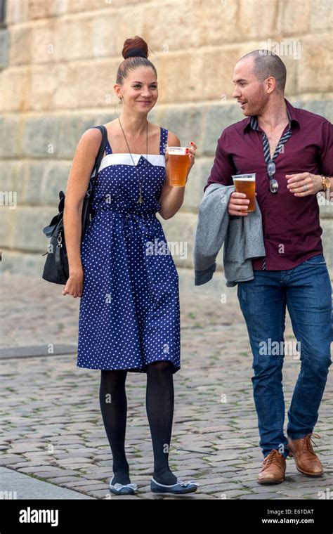 man and woman couple walking on the waterfront and drinking beer naplavka prague czech republic